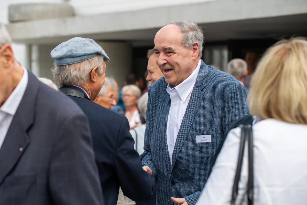 Mehrere Menschen stehen zusammen und reden und lachen. 